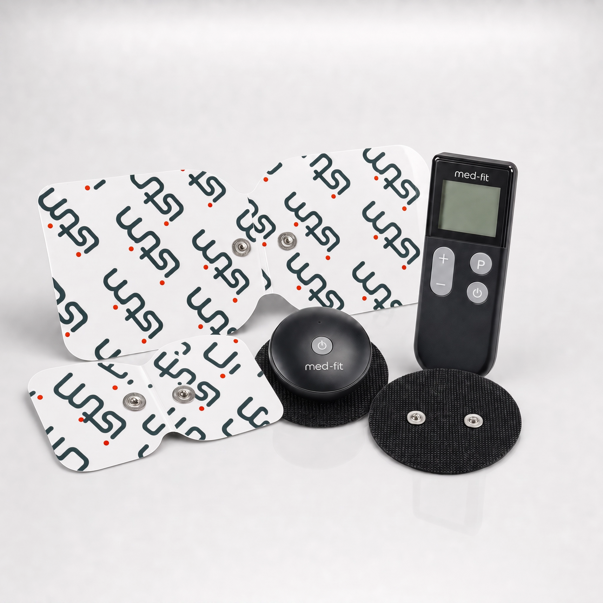 A med-fit TENS unit muscle stimulator kit with four white electrode pads printed with the med-fit logo, a black round controller, and two black adhesive gel pads on a light gray reflective surface.